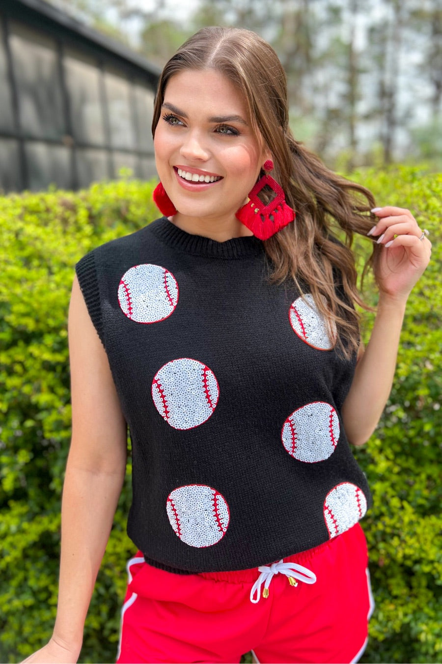 a black sleeveless sweater vest with an oversized fit, an allover textured baseball motif, and ribbed trim at the neckline, arm openings, and hem