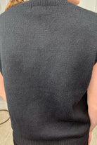 a black sleeveless sweater vest with an oversized fit, an allover textured baseball motif, and ribbed trim at the neckline, arm openings, and hem