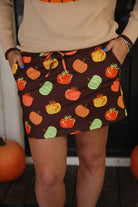 mid-rise relaxed fit everyday skort made of lightweight material with built-in brown shorts, drawstring tie with gold bead accents, an elastic band on the back, and side pockets, designed on a multicolor pumpkin print and brown base