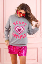  a gray long-sleeve pullover made from luxe material with chenille 'HEART BREAKER' lettering, a layered sequin heart detail, relaxed drop-shoulder fit, and ribbed neckline, cuffs, and hem for an effortlessly elevated look