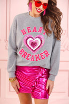  a gray long-sleeve pullover made from luxe material with chenille 'HEART BREAKER' lettering, a layered sequin heart detail, relaxed drop-shoulder fit, and ribbed neckline, cuffs, and hem for an effortlessly elevated look