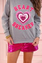  a gray long-sleeve pullover made from luxe material with chenille 'HEART BREAKER' lettering, a layered sequin heart detail, relaxed drop-shoulder fit, and ribbed neckline, cuffs, and hem for an effortlessly elevated look