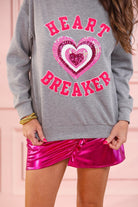  a gray long-sleeve pullover made from luxe material with chenille 'HEART BREAKER' lettering, a layered sequin heart detail, relaxed drop-shoulder fit, and ribbed neckline, cuffs, and hem for an effortlessly elevated look