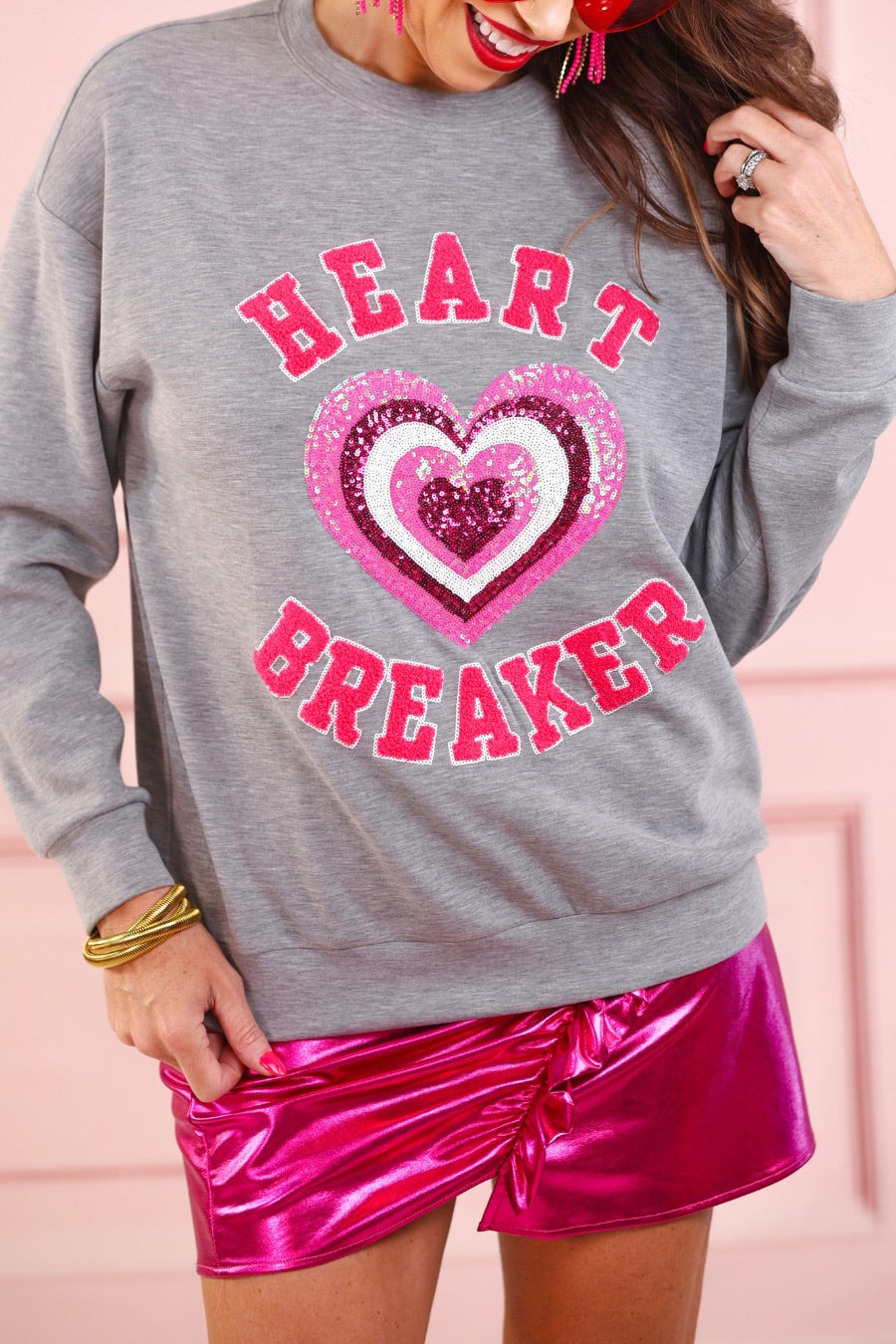  a gray long-sleeve pullover made from luxe material with chenille 'HEART BREAKER' lettering, a layered sequin heart detail, relaxed drop-shoulder fit, and ribbed neckline, cuffs, and hem for an effortlessly elevated look