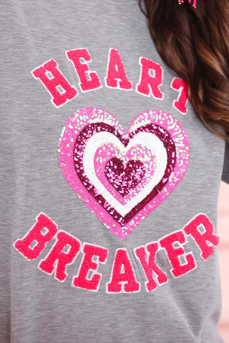  a gray long-sleeve pullover made from luxe material with chenille 'HEART BREAKER' lettering, a layered sequin heart detail, relaxed drop-shoulder fit, and ribbed neckline, cuffs, and hem for an effortlessly elevated look