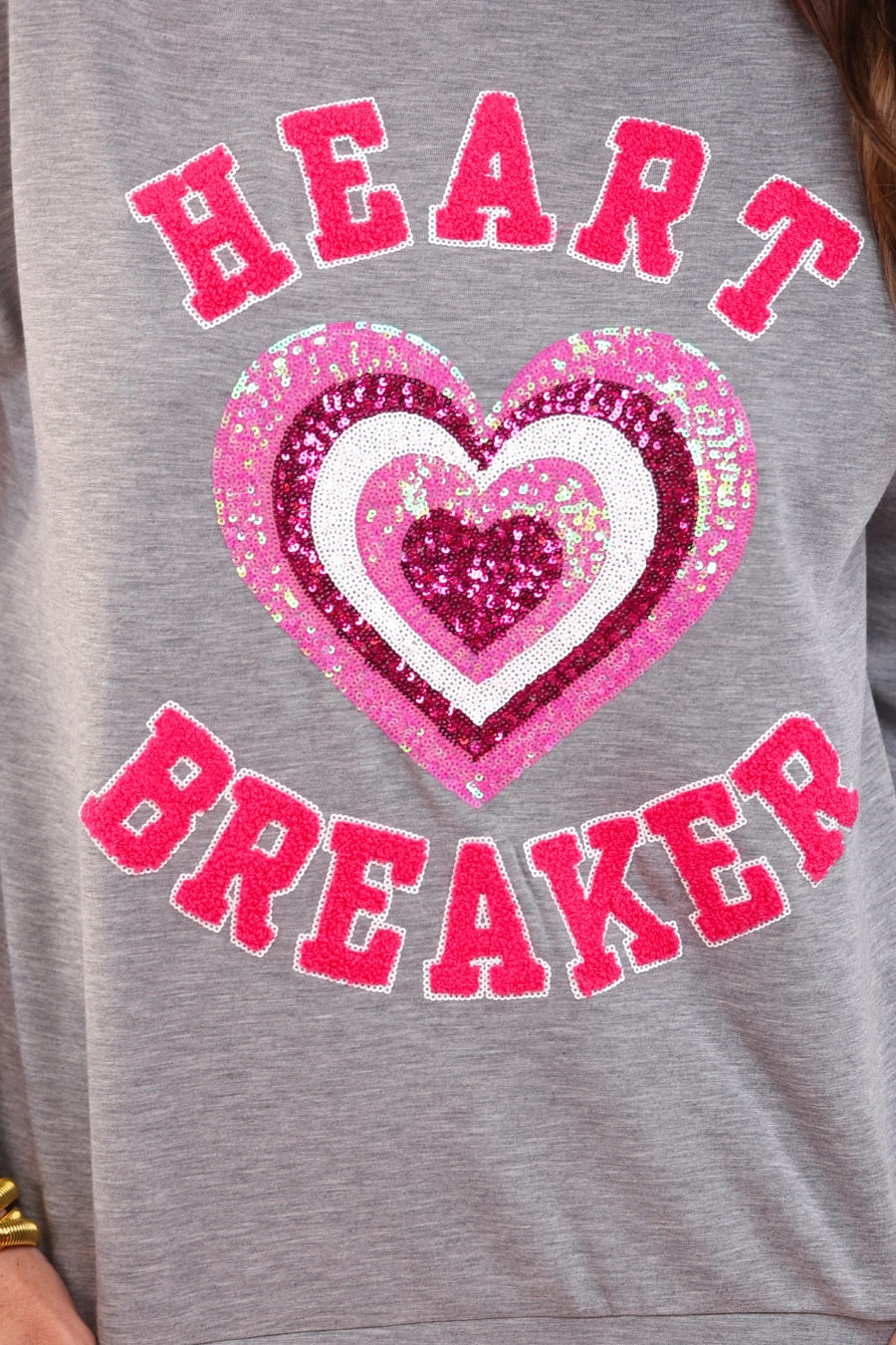  a gray long-sleeve pullover made from luxe material with chenille 'HEART BREAKER' lettering, a layered sequin heart detail, relaxed drop-shoulder fit, and ribbed neckline, cuffs, and hem for an effortlessly elevated look