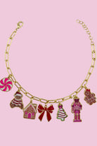 an adjustable gold link bracelet adorned with whimsical enamel charms (a bold red bow, Christmas bear, Christmas tree, gingerbread girl, gingerbread house, pink nutcracker, and a pink peppermint)
