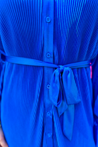 a royal blue pleated shirt dress with a classic collar, functional button front, removable waist sash, drop shoulder long sleeves, satin cuffs, back yoke seam, accordion texture, and flowy mini-length silhouette