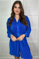 a royal blue pleated shirt dress with a classic collar, functional button front, removable waist sash, drop shoulder long sleeves, satin cuffs, back yoke seam, accordion texture, and flowy mini-length silhouette