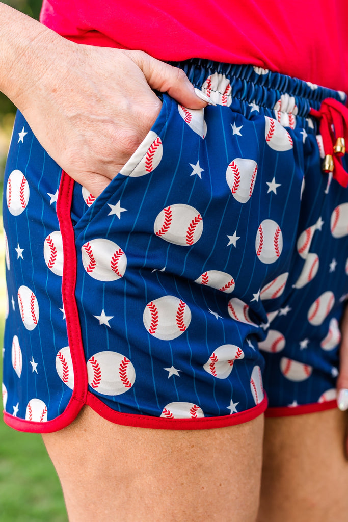 mid-rise, tie waist drawstring with gold bead accent, side pockets, & relaxed fit on a baseball, stars, & white stripe pattern on blue with red piping & gold accent bead