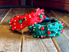 top knot adorned with jewel-tone beads, pearls, and rhinestones on velvet in green and red