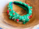 top knot adorned with jewel-tone beads, pearls, and rhinestones on velvet in green