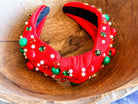 top knot adorned with jewel-tone beads, pearls, and rhinestones on velvet in red