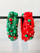 top knot adorned with jewel-tone beads, pearls, and rhinestones on velvet in green and red