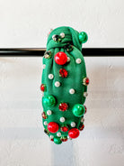 top knot adorned with jewel-tone beads, pearls, and rhinestones on velvet in green