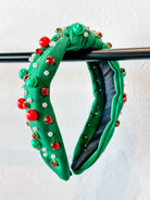 top knot adorned with jewel-tone beads, pearls, and rhinestones on velvet in green