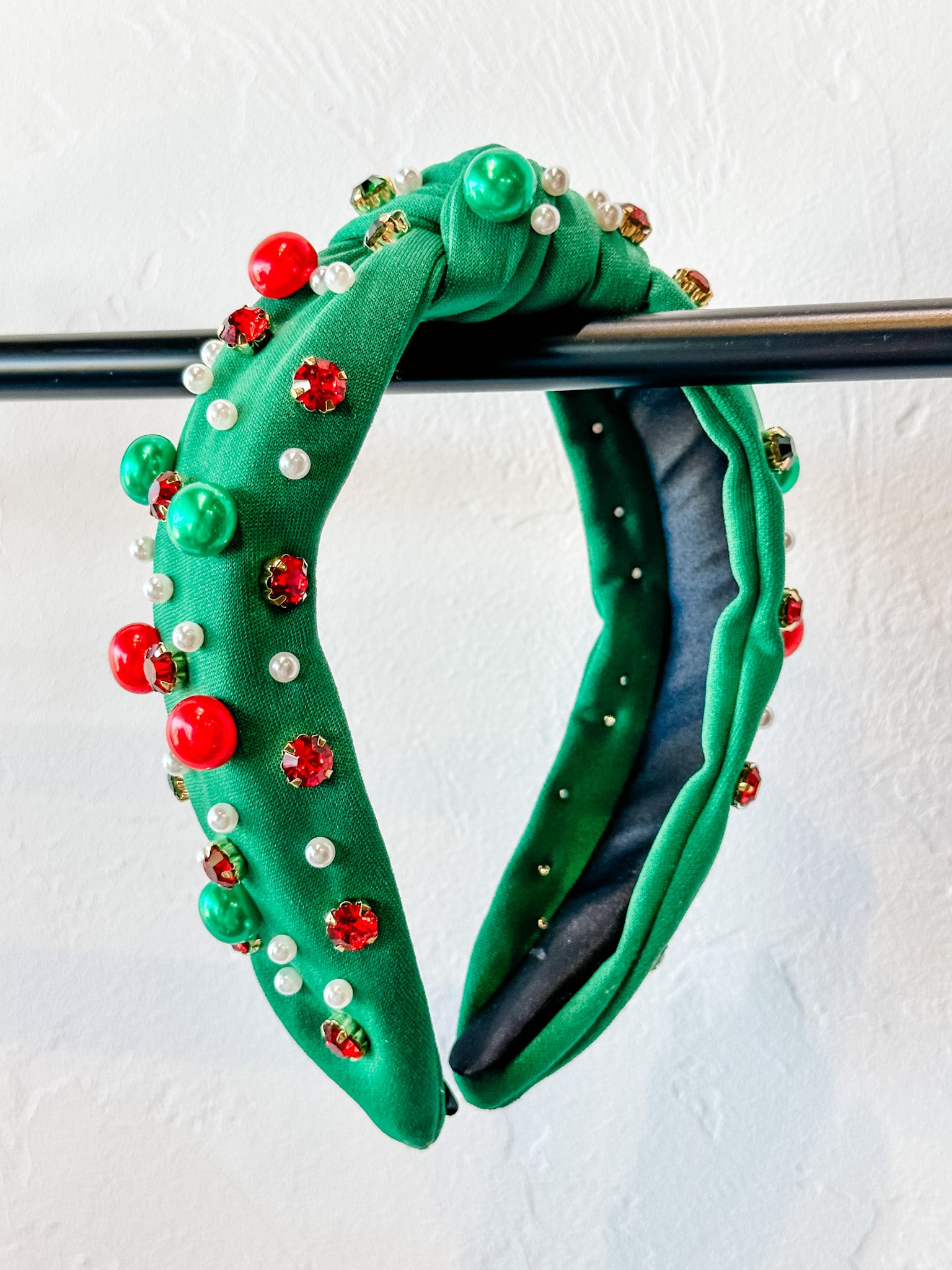 top knot adorned with jewel-tone beads, pearls, and rhinestones on velvet in green