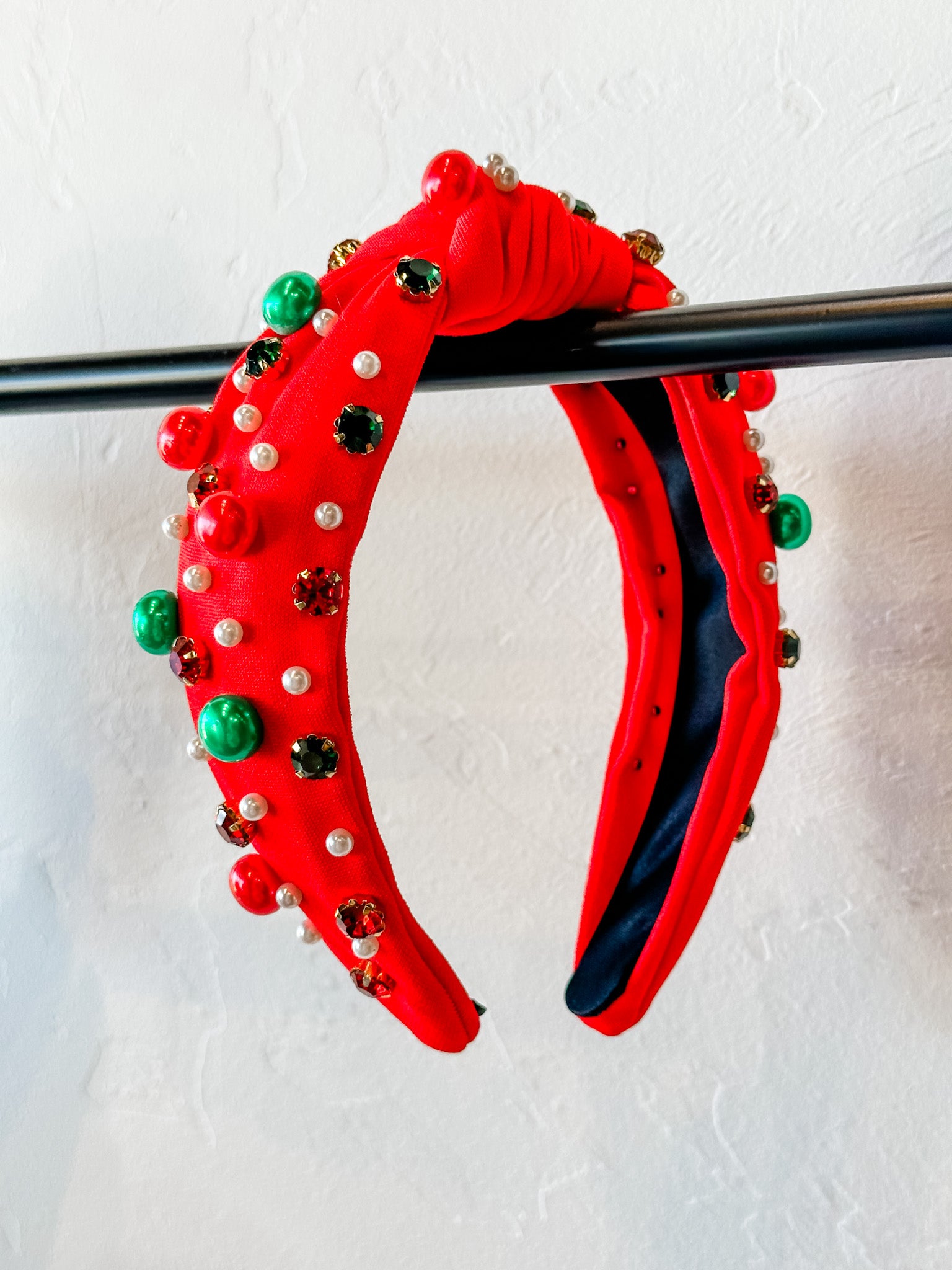 top knot adorned with jewel-tone beads, pearls, and rhinestones on velvet in red