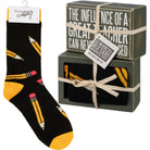 Black socks with yellow and pink accents and a decorative box with text.