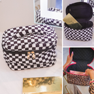 a structured bag with a spacious interior, a secure double zip around closure, a top handle, and gold accents on a quilted body in checkerboard checkered (black/white) and safari chic (leopard)