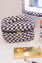 a structured bag with a spacious interior, a secure double zip around closure, a top handle, and gold accents on a quilted body in checkerboard checkered (black/white)