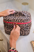 a structured bag with a spacious interior, a secure double zip around closure, a top handle, and gold accents on a quilted body in safari chic (leopard)