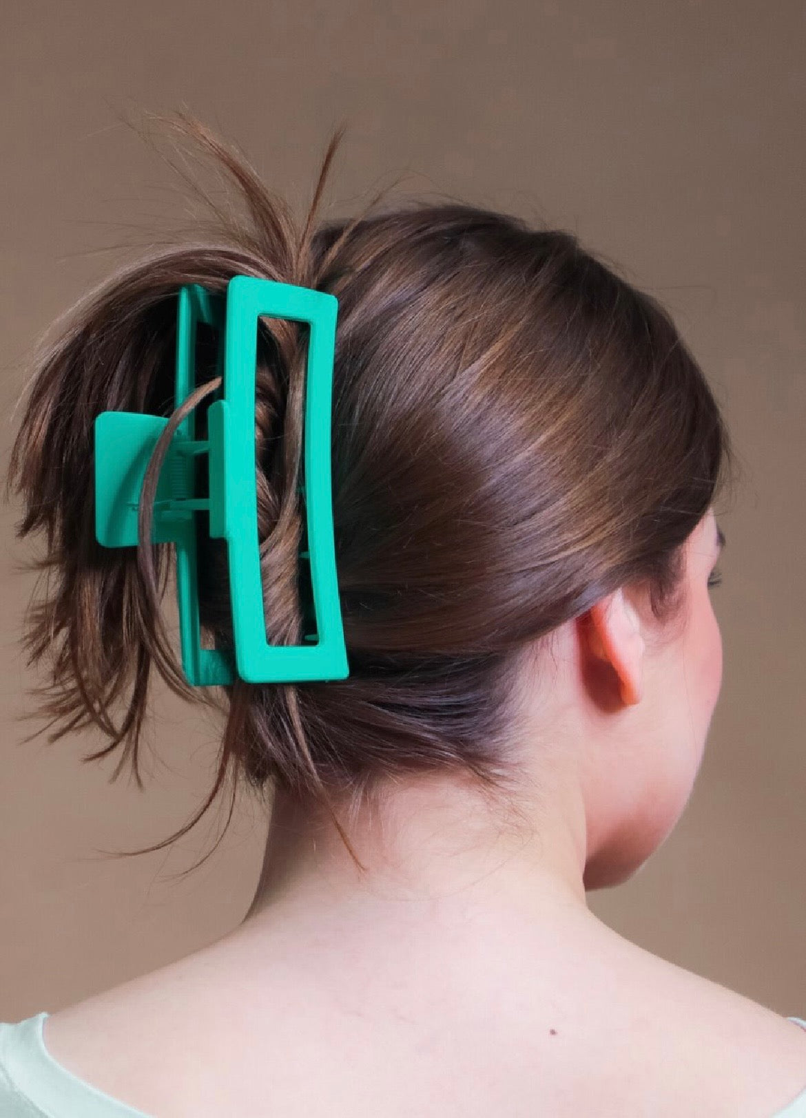 Close-up of a person's hair with a teal hair clip.