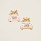 Pair of 'Just Married' wedding car earrings on a light beige background