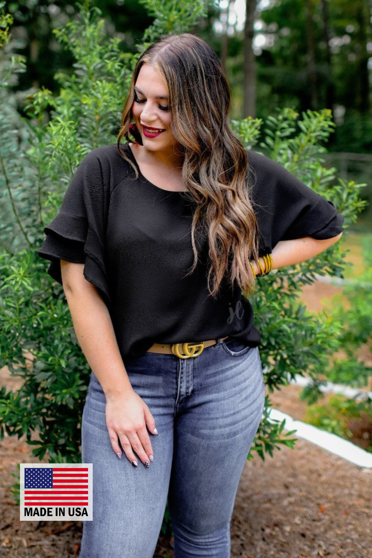 a black true-to-size blouse crafted from lightweight textured fabric with a rounded neckline, tiered ruffle sleeves, and a relaxed drape, accented by a MADE IN USA watermark in the bottom left-hand corner