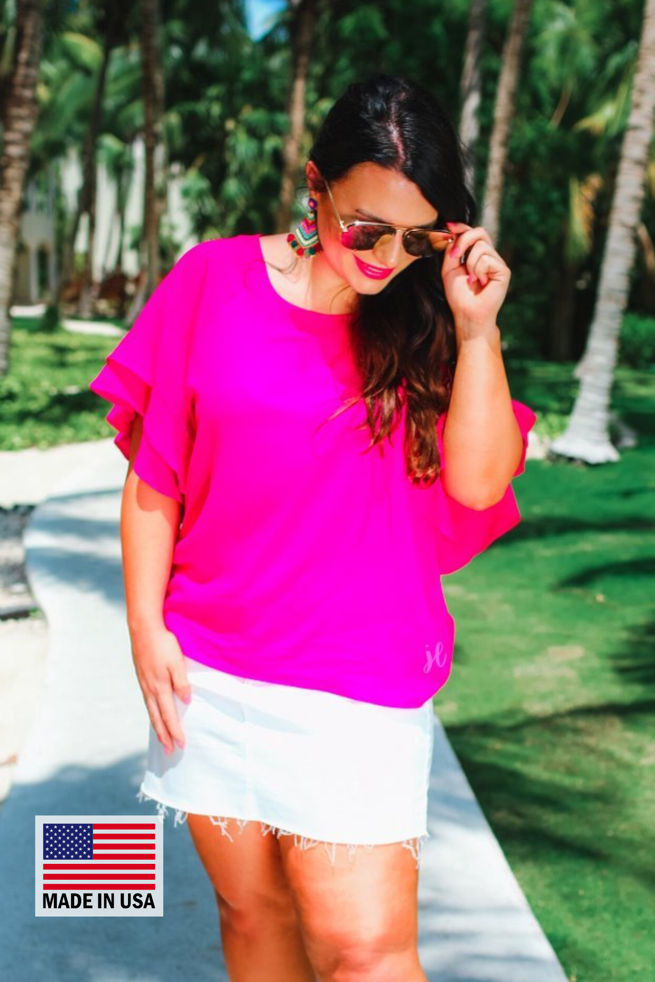 a pink true-to-size blouse crafted from lightweight textured fabric with a rounded neckline, tiered ruffle sleeves, and a relaxed drape, accented by a MADE IN USA watermark in the bottom left-hand corner