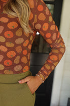 long-sleeve mesh top with a mock neckline and a lettuce hem on a multicolor pumpkin print and brown base