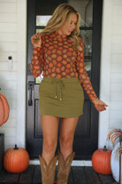 long-sleeve mesh top with a mock neckline and a lettuce hem on a multicolor pumpkin print and brown base
