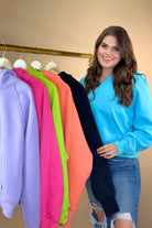 a cropped hooded quarter zip pullover with a relaxed fit, functional kangaroo pocket, and thumb holes in aqua, black, coral, lavender, neon lime, and pink