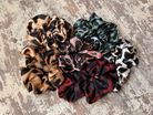 oversized satin-look leopard scrunchies with glossy animal print fabric, plush gathered construction, lightweight feel, and gentle hair-friendly hold in beige, chocolate, mauve, rose, teal, and white