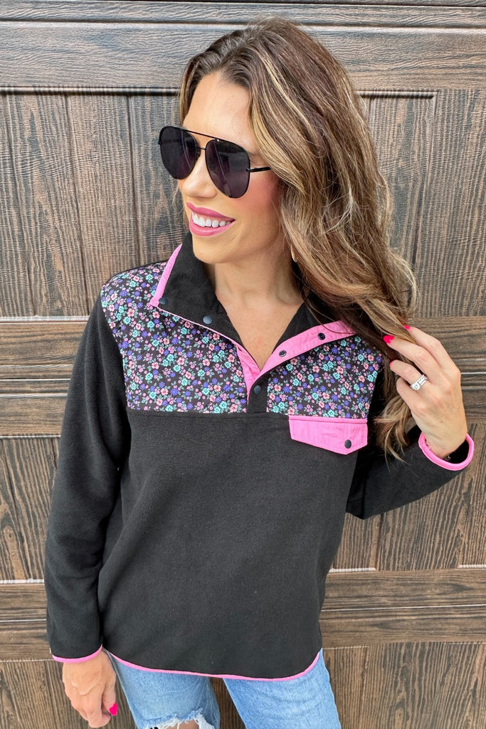 black fleece with floral print, pops of pink detailing, and snaps