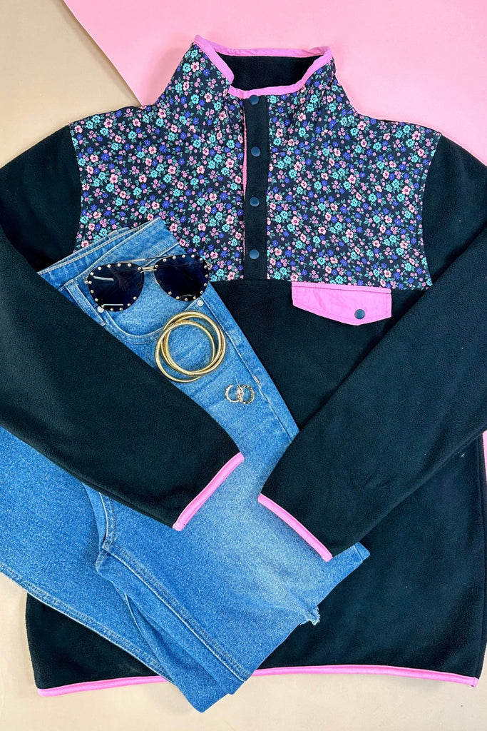 black fleece with floral print, pops of pink detailing, and snaps