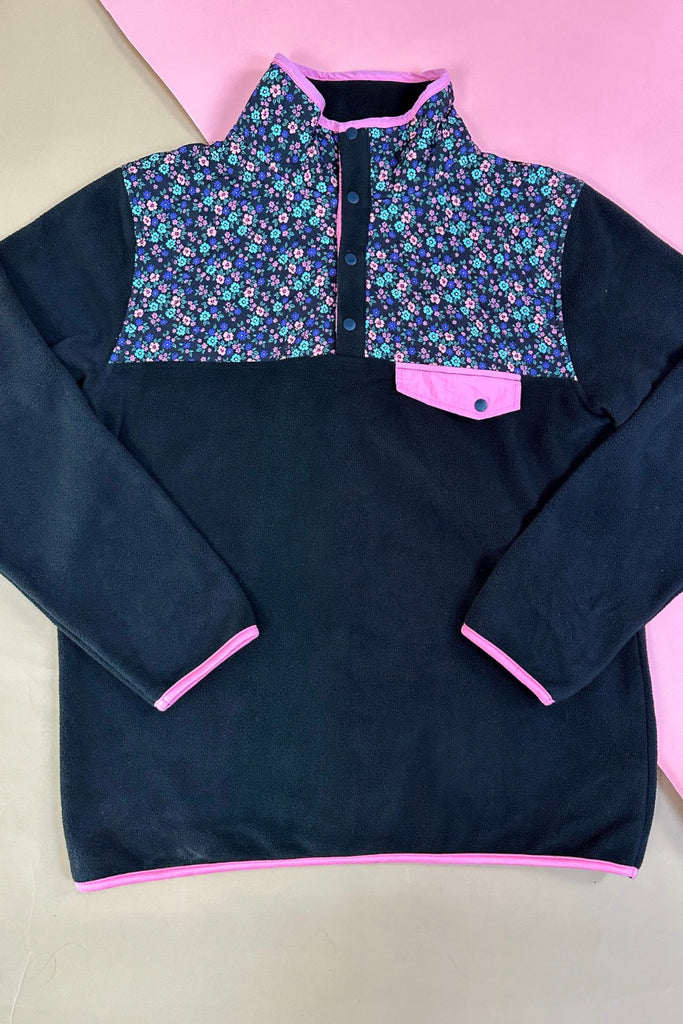 black fleece with floral print, pops of pink detailing, and snaps