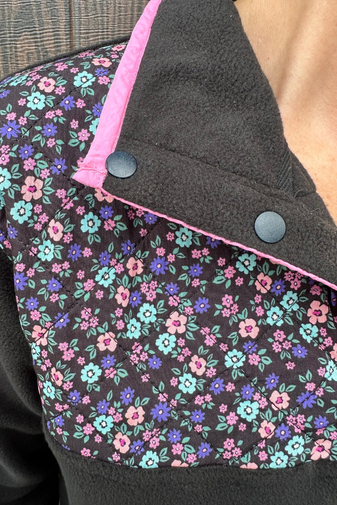 black fleece with floral print, pops of pink detailing, and snaps