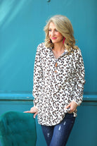 a long-sleeve pullover with a quarter zip, foldable collar, and a side split hem on a neutral leopard pattern fleece fabric