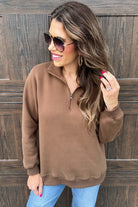 long-sleeve pullover made of cozy fabric with a quarter zip, cuffs, and a split waistband hem in brown