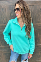 long-sleeve pullover made of cozy fabric with a quarter zip, cuffs, and a split waistband hem in turquoise