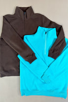 long-sleeve pullover made of cozy fabric with a quarter zip, cuffs, and a split waistband hem in brown and turquoise