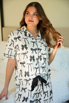 short sleeve top and matching pants on white base with a black bow pattern, black piping, and black ruffle trim