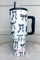 40-ounce white tumbler with a black bow and ribbon pattern print design, handle, screw-on lid, and a reusable straw