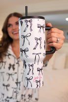 40-ounce white tumbler with a black bow and ribbon pattern print design, handle, screw-on lid, and a reusable straw