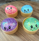 a mystery bead-filled mini dumpling squishy with assorted colors, iridescent shimmer, kawaii face, steamer-style container, and soft sensory texture in blue, green, pink, and purple