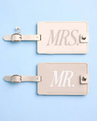 Two beige luggage tags with 'MR.' and 'MRS.' text on a light blue background