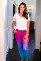 relaxed fit mid-rise joggers with side pockets and a tie waist drawstring, designed on a magenta to turquoise ombré print fabric with turquoise trim