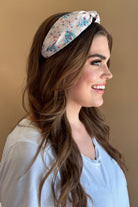 a twisted center knot crafted from lightweight fabric with holiday pattern print including Christmas trees, twinkling string lights, ornaments, and a 'ho ho ho' print&nbsp;