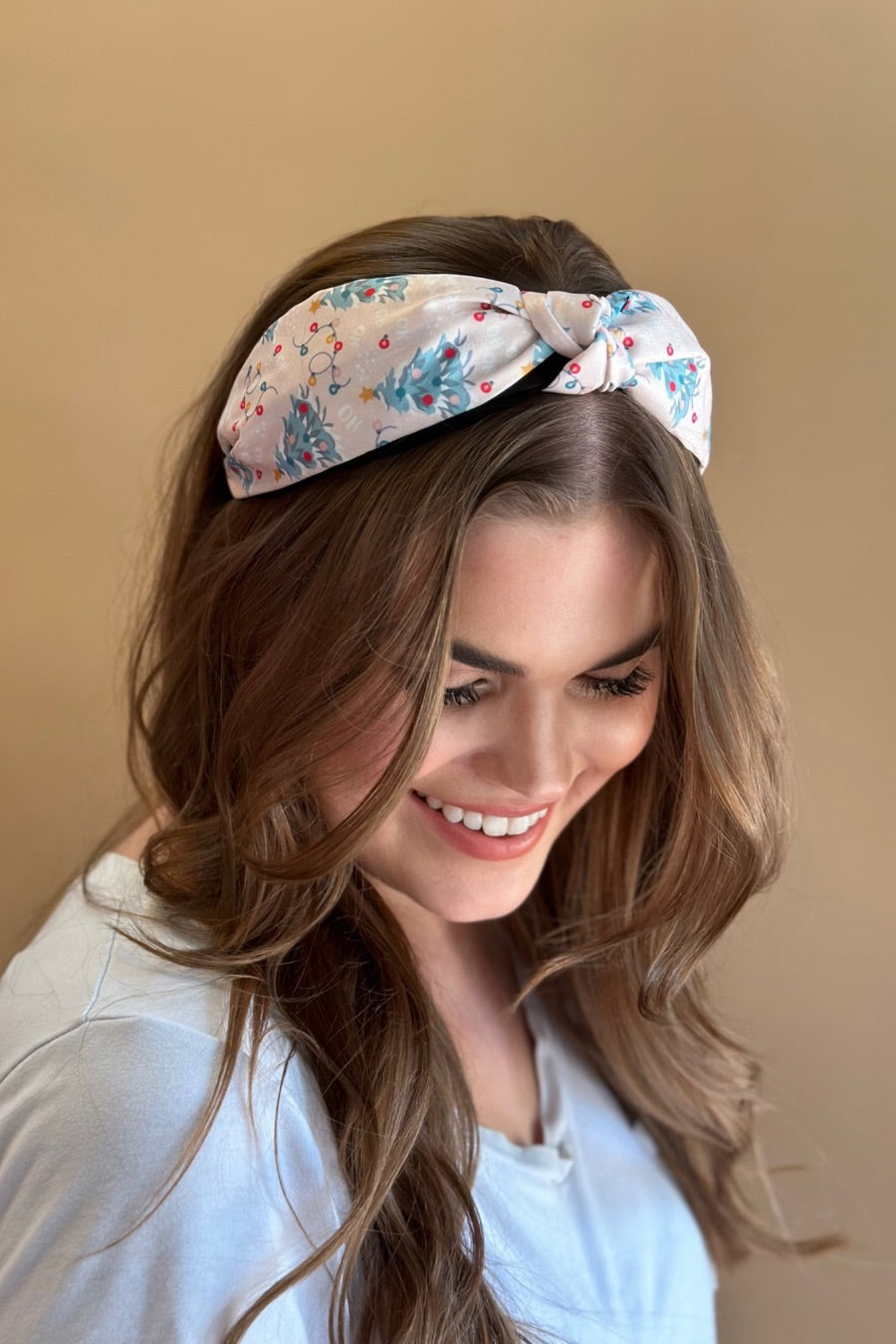 a twisted center knot crafted from lightweight fabric with holiday pattern print including Christmas trees, twinkling string lights, ornaments, and a 'ho ho ho' print&nbsp;